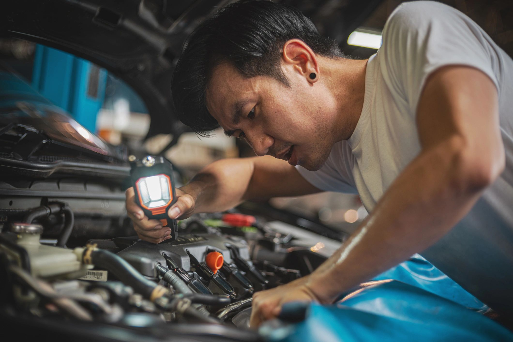 Technician examining a vehicle engine during electrical diagnostics